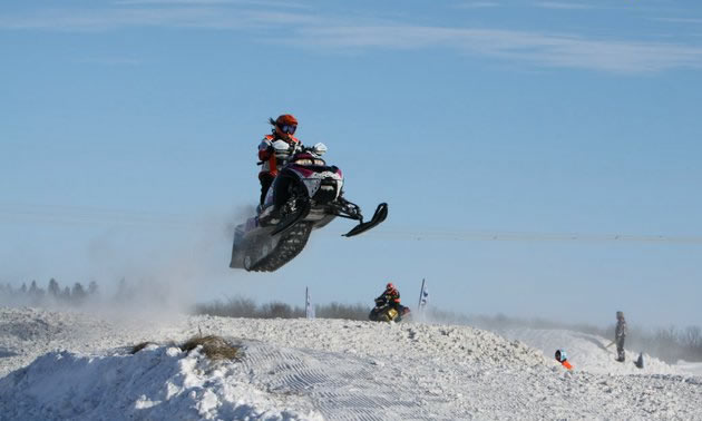 Girl in the air on a snowmobile.