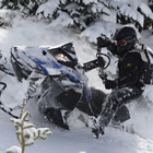 Photo of a guy riding a blue and black coloured sled up a steep hill.