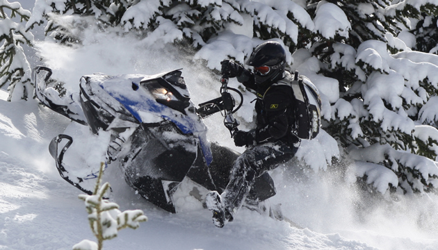 Photo of a guy riding a blue and black coloured sled up a steep hill.