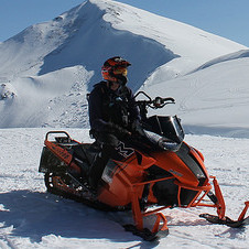 A sledder sitting on his snowmobile. 