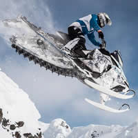 A man soaring through the air on a sled in the mountains of Finland.