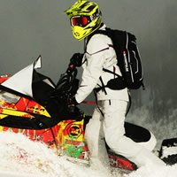 A woman in an all-white sledding outfit on an Pro-RMK. 