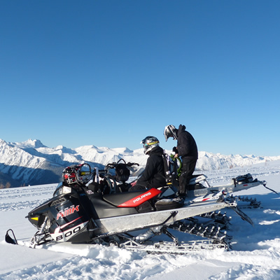 Mountain snowmobilers sitting on top of a mountain on a bluebird day. 