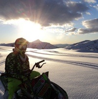 Nadine Overwater sitting on her sled enjoying the view of the sun going down over the snowcovered mountains. 
