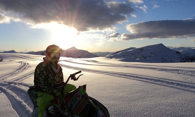 Nadine Overwater sitting on her sled enjoying the view of the sun going down over the snowcovered mountains. 