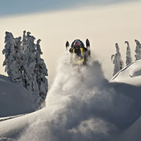 A shot of the back of a snowmobiler as he's going over a windlip.