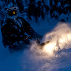 A snowmobiler riding in the dark. 