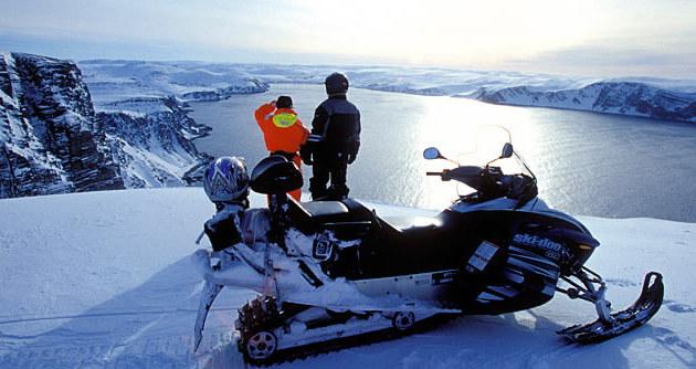 Snowmobilers looking down at a fjord in Norway. 