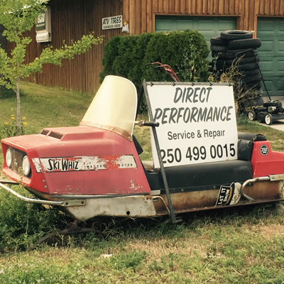 A picture of a vintage Ski-Whiz snowmobile with an advertising sign sitting on top of it. 