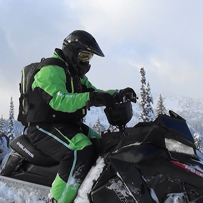 A man sitting on his snowmobile. 