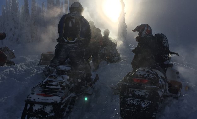 Snowmobilers parked on a foggy day. 