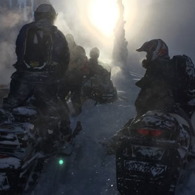 Snowmobilers parked on a foggy day. 
