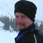 A man in a black toque in the mountains. 