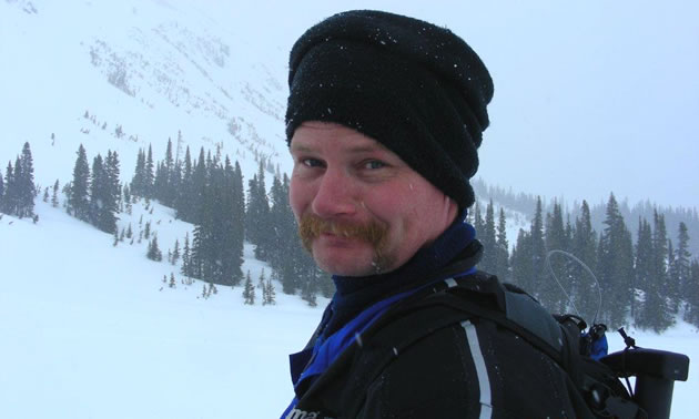 A man in a black toque in the mountains. 