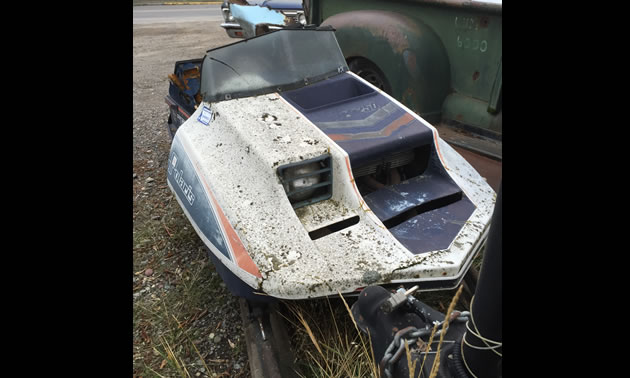 A rusty and dented Polaris TX 250 snowmobile. 
