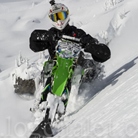 A man in a white helmet on a green snow bike. 