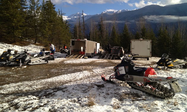 A mountain sled and trailers parked at a parking lot. 