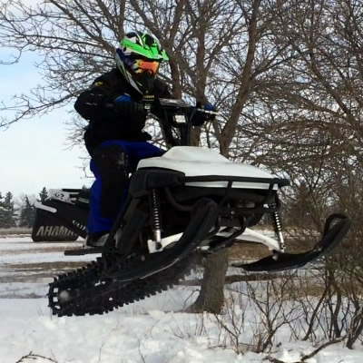 A young boy airing out a Yamaha SnoSport. 
