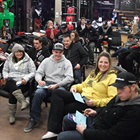 A group of people sitting on chairs in a snowmobile shop. 