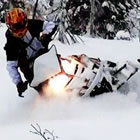 A woman in a red helmet riding a snowmobile through deep snow.