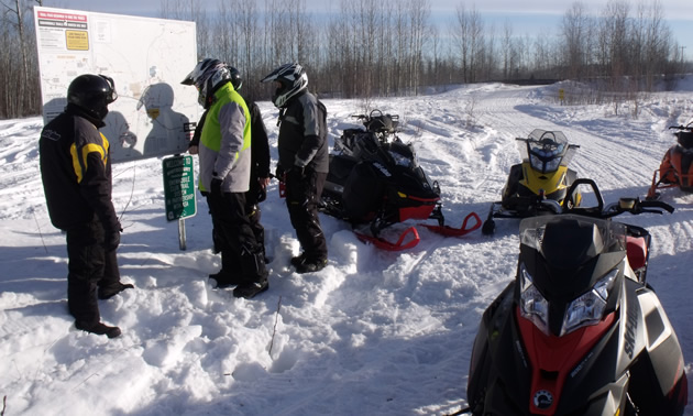 Snowmobilers looking at a map at the trailhead. 