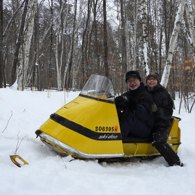 Bruce and Ellen Hostetler sitting on bright yellow Ski-Doo. 