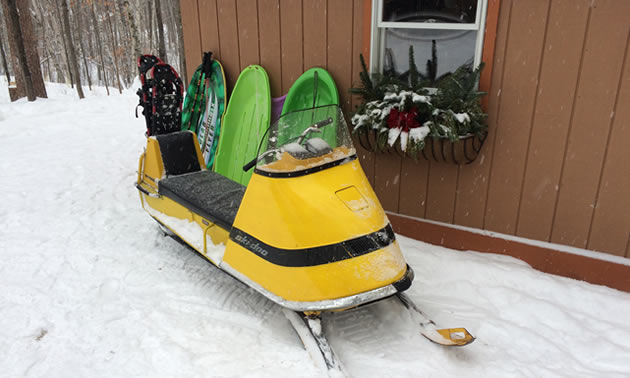 Ski-Doo sitting in front of cabin. 