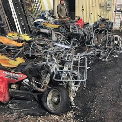 Burnt sleds and ATV's sitting outside a business. 