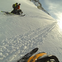 A photo of two guys riding tandem on a snowmobile. 