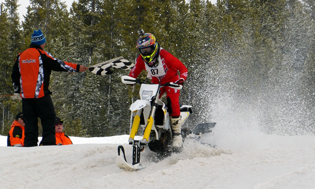 FMX rider Justin Homan taking the checkered flag in a snow bike race. 