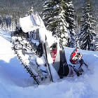 Photo of the back end of a snowmobile sticking out of the snow. 