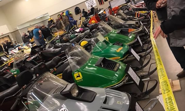 Line-up of snowmobiles in indoor arena. 