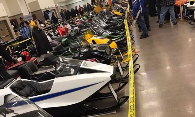 Line-up of snowmobiles in indoor arena. 