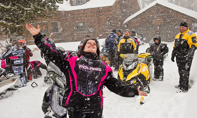 Snowmobiler throwing her hands up in joy at the snow falling. 
