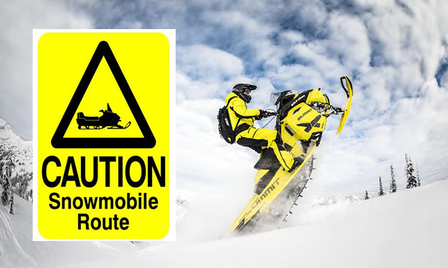 Person on snowmobile, with 'Caution - Snowmobile route' sign. 