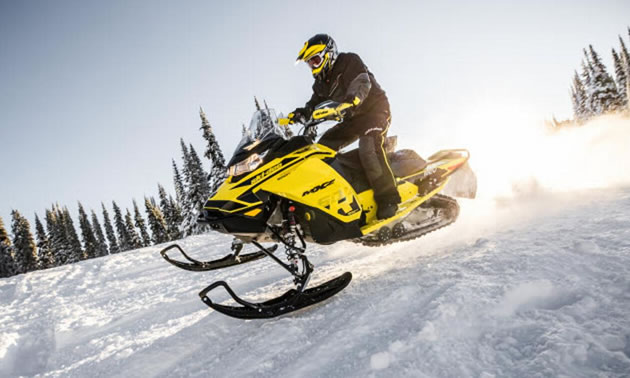 Person riding a yellow snowmobile. 