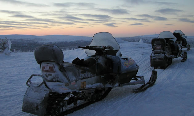 Snowmobiles with sunset in background. 
