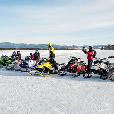 Group of snowmobilers lined up in a row. 