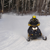 A snowmobiler coming down a snowmobile trail. 