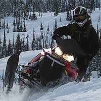 A sledder riding toward the camera on a red sled. 