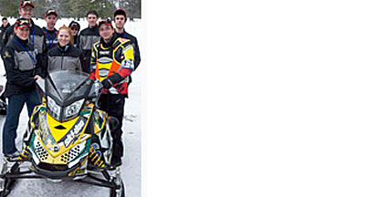 Photo of people standing next to a snowmbile