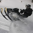 A man in black on a black snowmobile. 