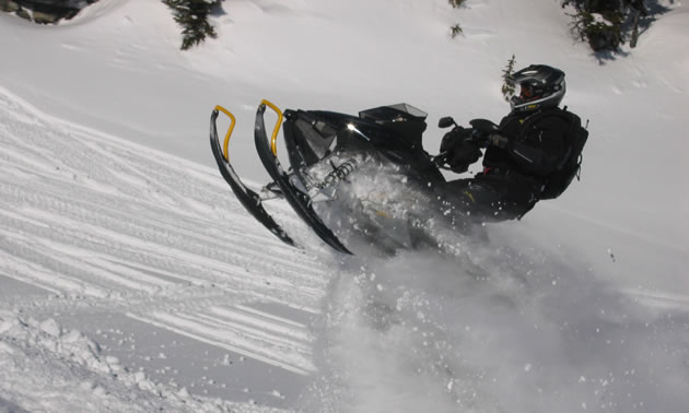 A man in black on a black snowmobile. 