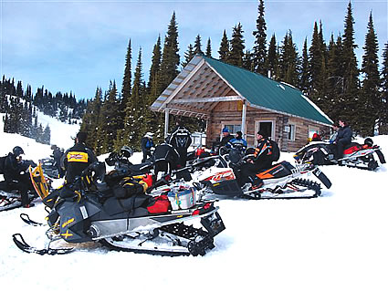 People on sleds in front of a cabin