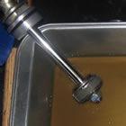 A long metal shock sitting in a pan of yellow liquid. 
