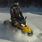 Photo of a guy riding a yellow sled through fresh powder. 