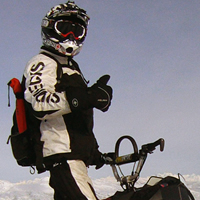 A man on a snowmobile with his thumbs up. 