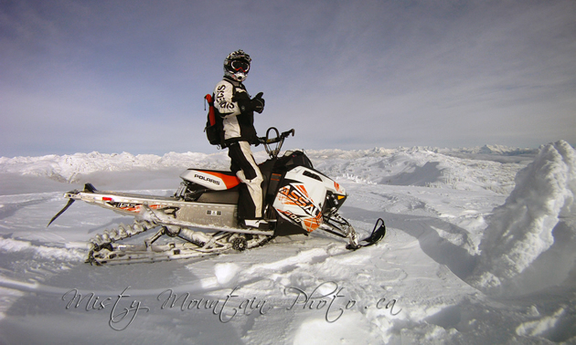 A man on a snowmobile with his thumbs up. 