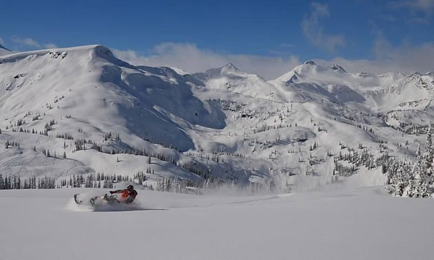 A snowmobiler in a mountain bowl. 