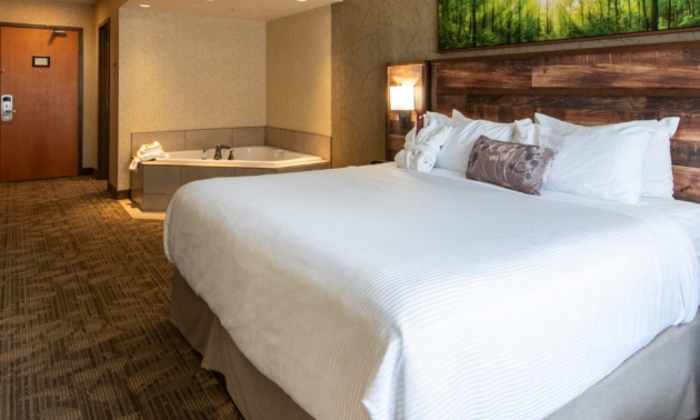 A hotel room with king size bed and jacuzzi tub in the corner
